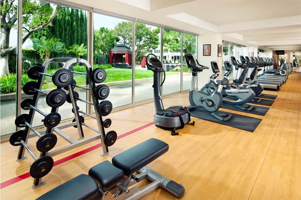 Fitness center with free weights, exercise bikes, and large windows to grounds