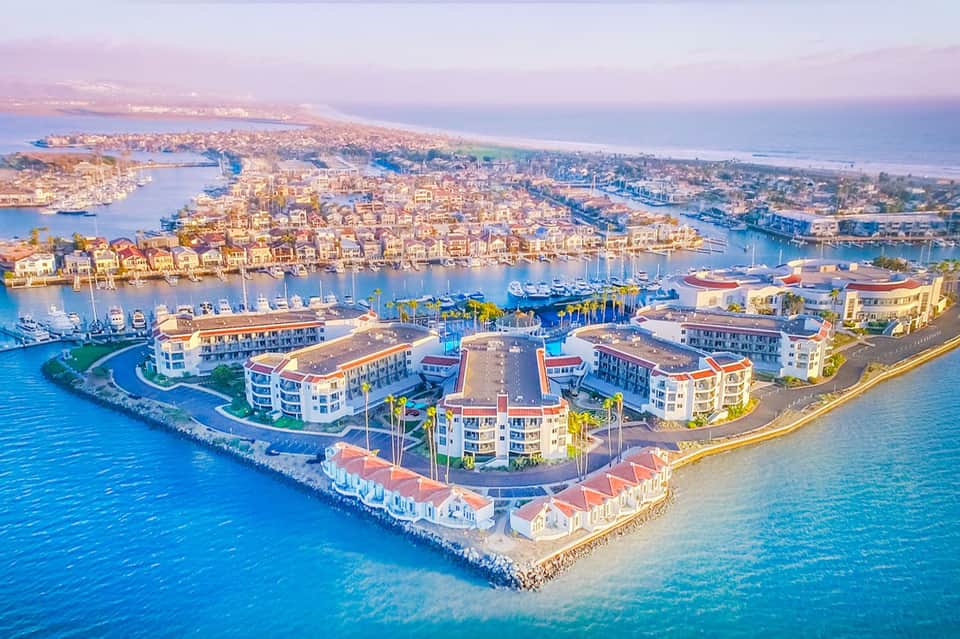 Aerial view of waterfront resort with boats, turquoise waters, and coastal neighborhood