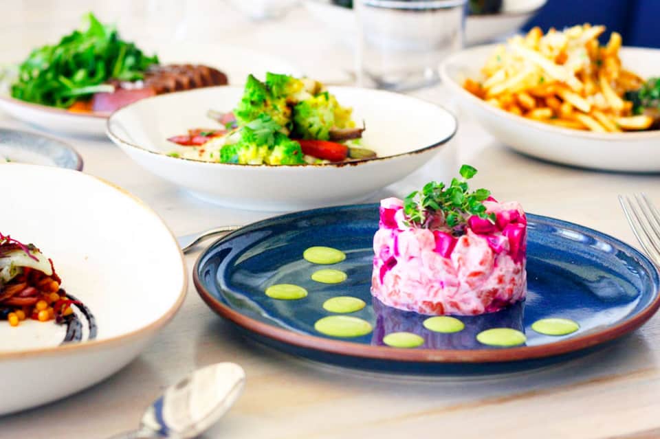 Fine dining restaurant table with beet carpaccio, broccoli, and colorful plated dishes