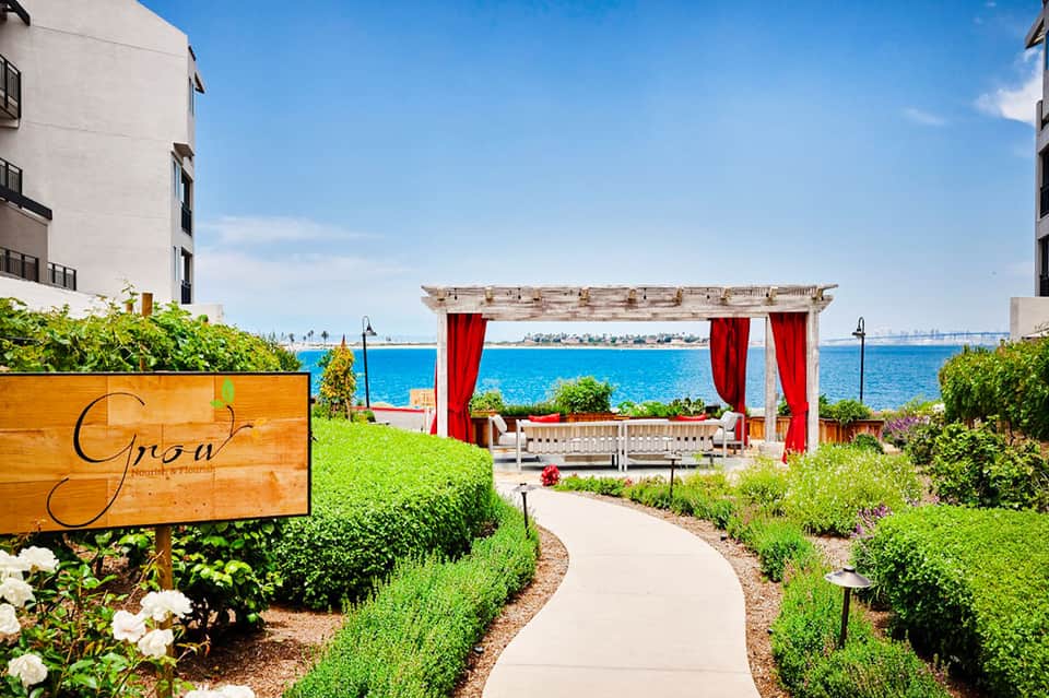 Waterfront garden with red pergola, ocean views, and landscaped pathways leading to beachfront seating area