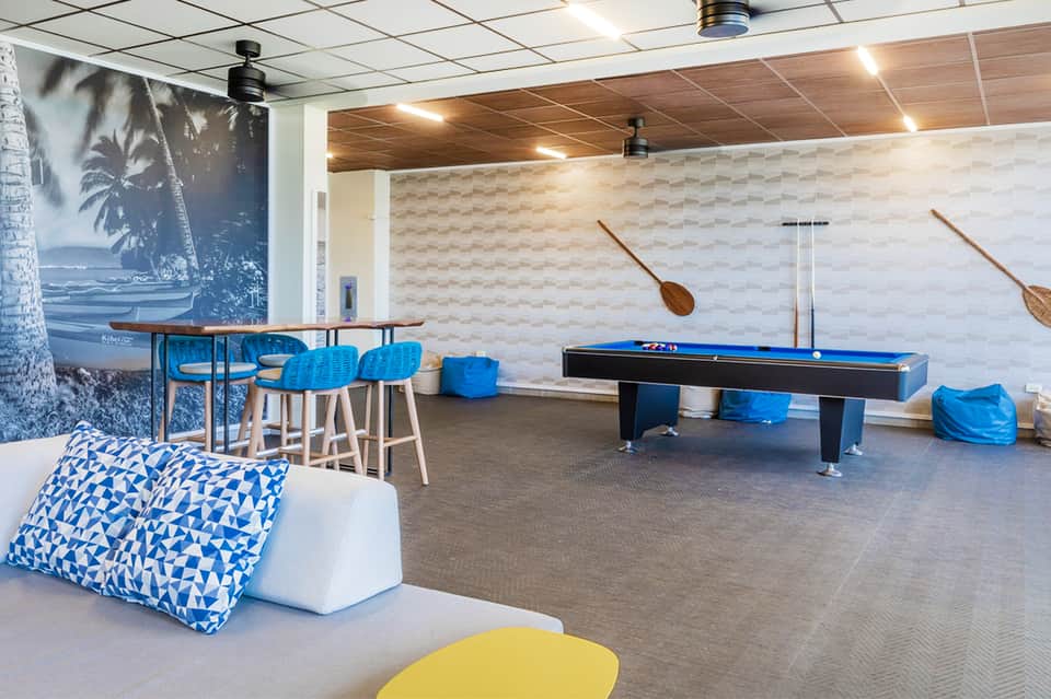 Recreation room with pool table, blue bar stools, palm artwork, and geometric wall patterns