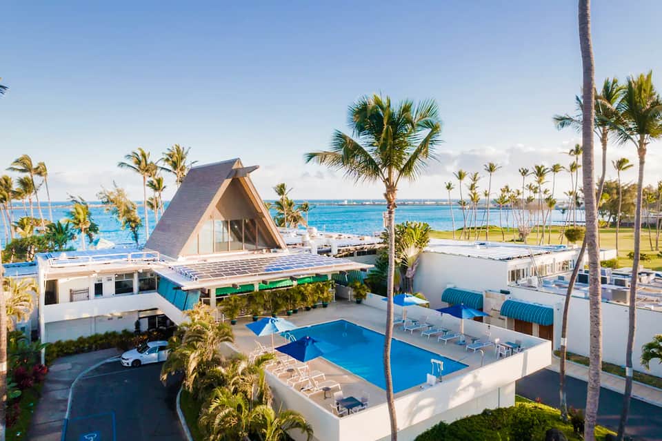 Oceanfront resort pool with modern architecture, palm trees, and coastal water views