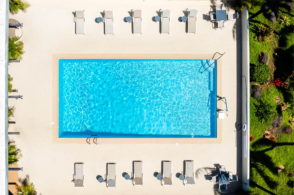 Aerial view of rectangular pool with lounge chairs on sandy deck