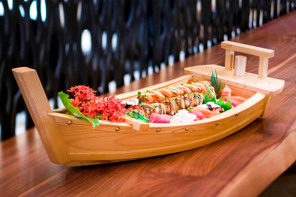 Decorative sushi boat display with grilled fish and fresh ingredients