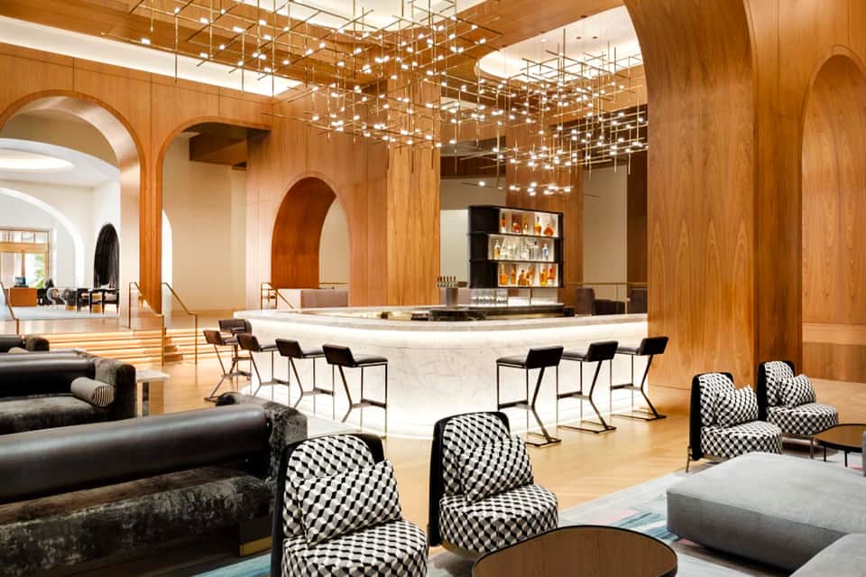 Luxury hotel lobby with wooden arches, marble bar, hanging crystal chandelier, and modern furnishings