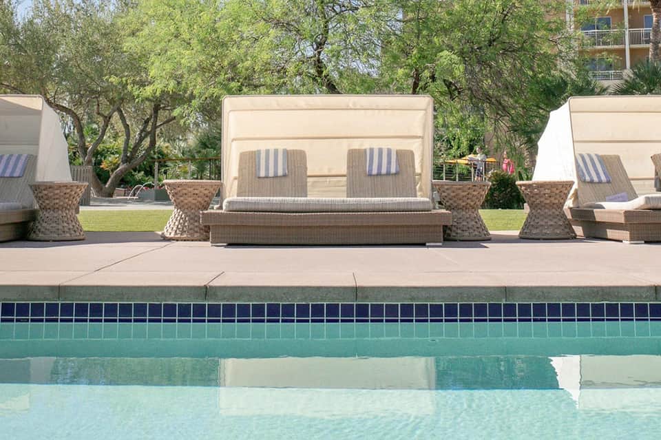 Luxurious poolside cabanas with striped cushions and woven accent tables