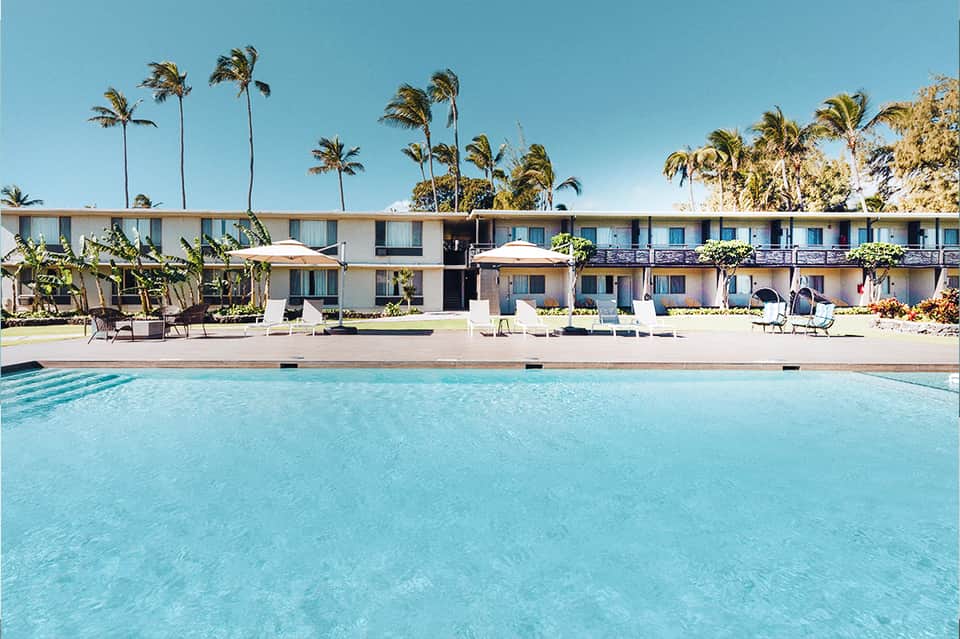 Mid-century modern motel with turquoise pool, palm trees, and retro architecture