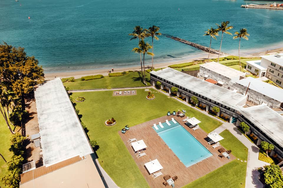 Aerial view of beachfront resort with pool, palm trees, and direct beach access to turquoise water