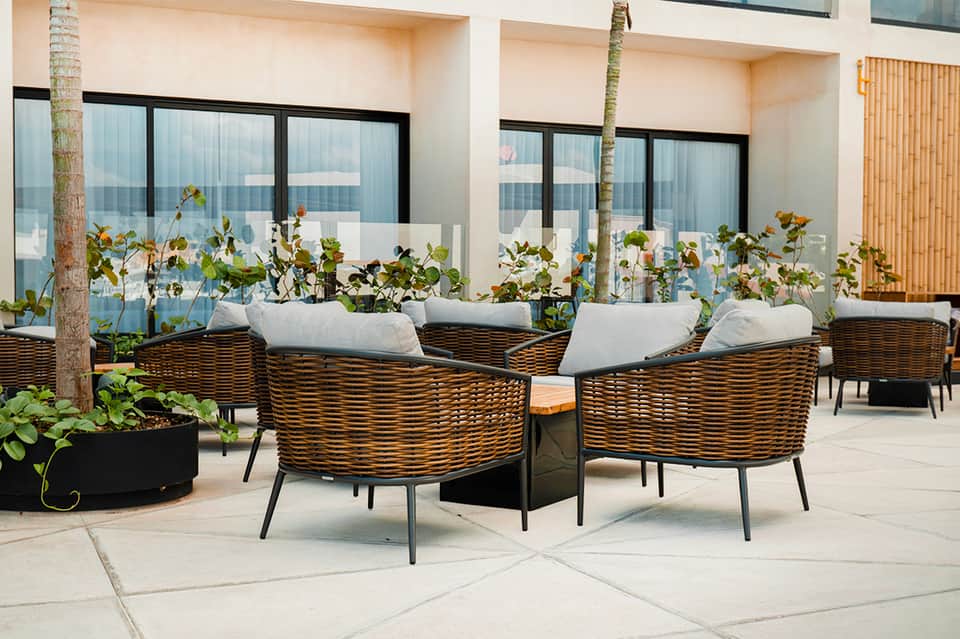 Wicker armchairs with white cushions on modern terrace with ocean views
