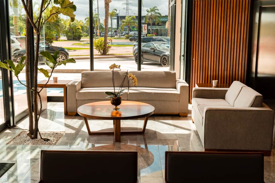 Contemporary hotel lobby with neutral sofas, wood accents, and street-facing windows