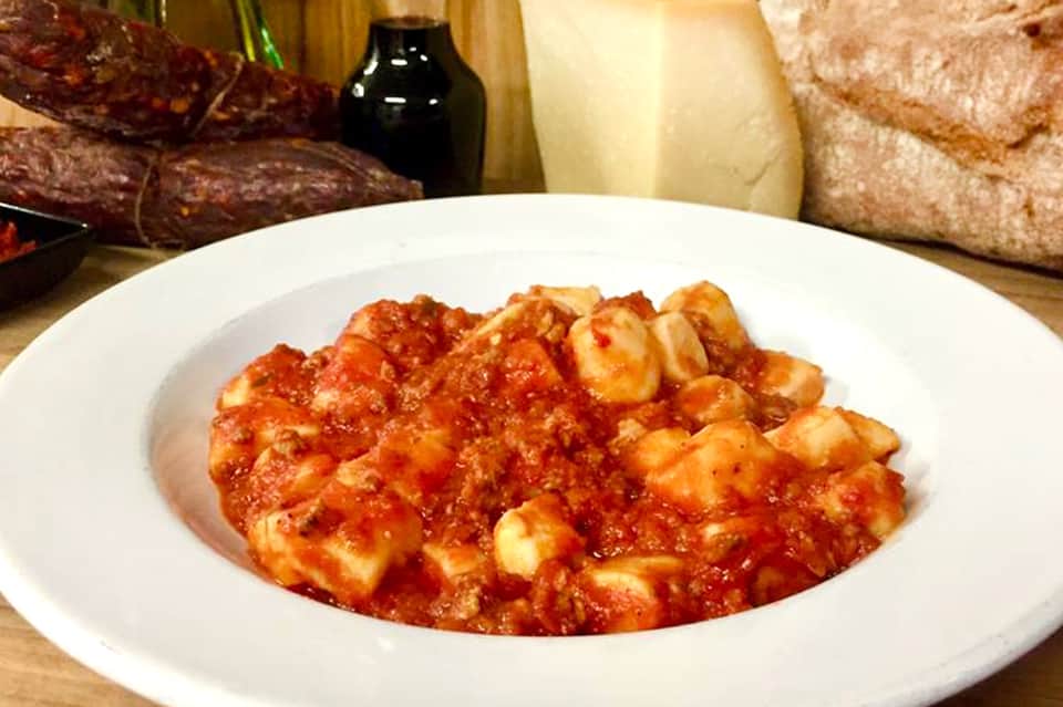 Traditional tomato-based pasta dish with cheese and herbs, served with bread and wine