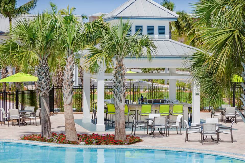 Resort pool area with white pergola, palm trees, and lounge seating