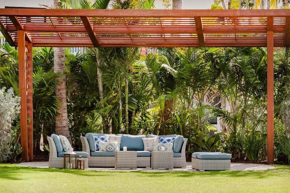Contemporary outdoor lounge with woven furniture and pergola in tropical garden setting