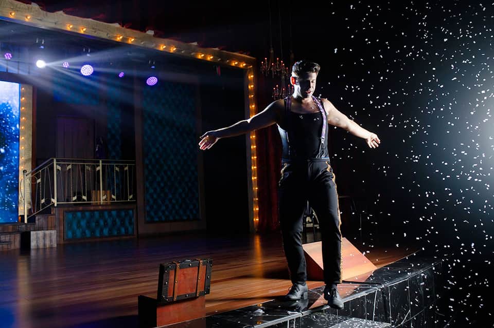 Male performer on illuminated stage with confetti effect during theatrical show production