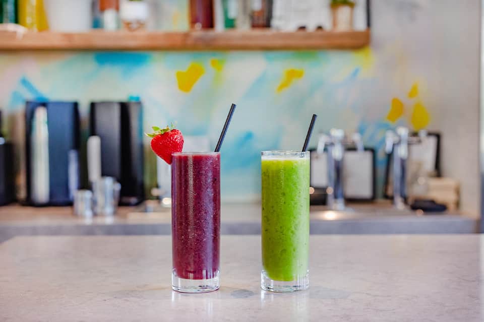 Two colorful smoothie drinks at juice bar counter