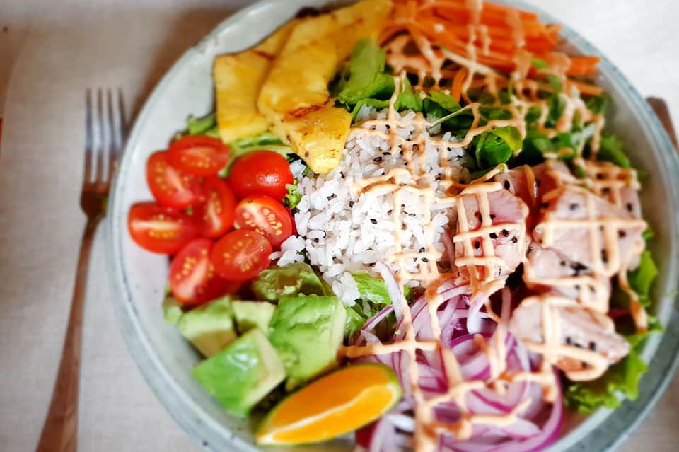 Colorful Asian salad bowl with rice, vegetables, pineapple, and fresh herbs