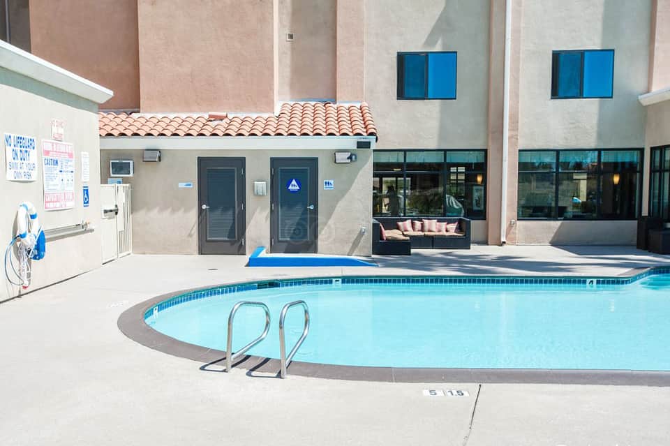 Resort pool with lounge chairs and spa building featuring Spanish tile roof and blue windows