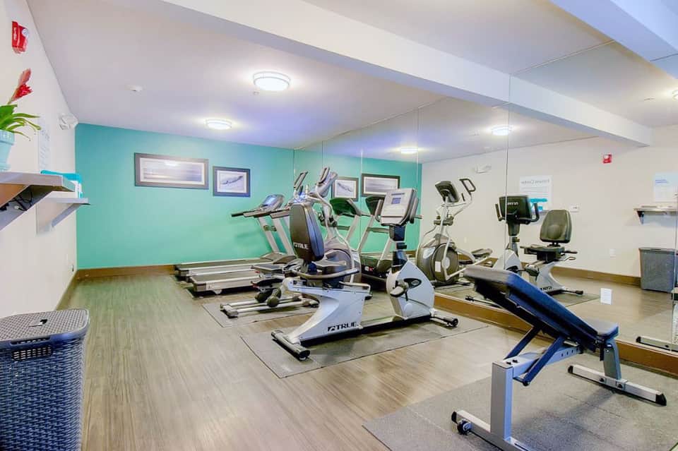 Bright fitness center with turquoise accent wall, treadmills, stationary bikes, and exercise equipment