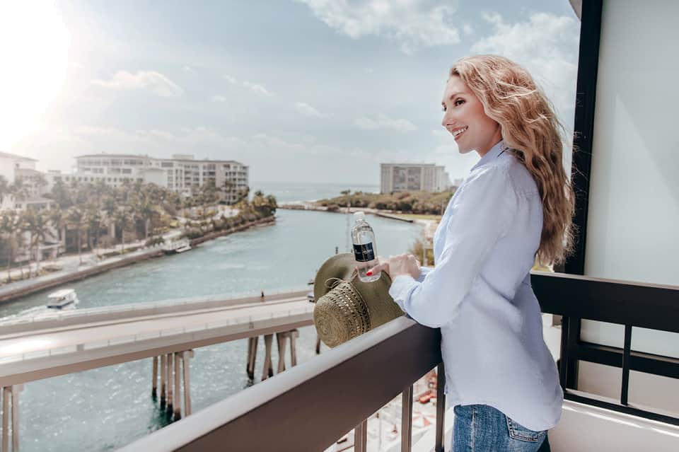 Woman on a high-rise balcony overlooking turquoise inlet water and coastal resort buildings