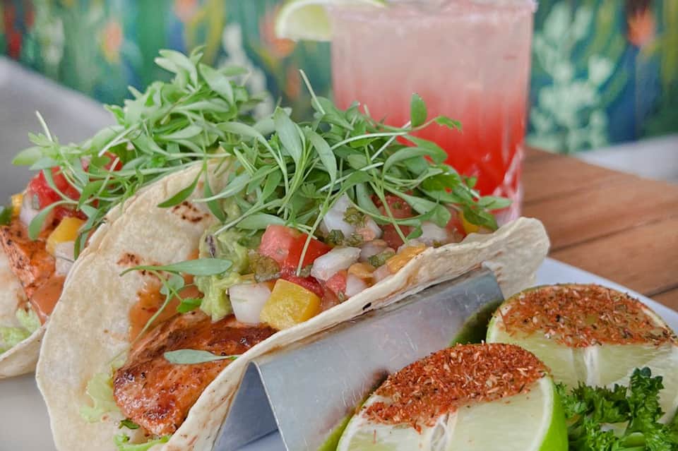 Tacos with fresh microgreens and colorful beverage in tropical setting