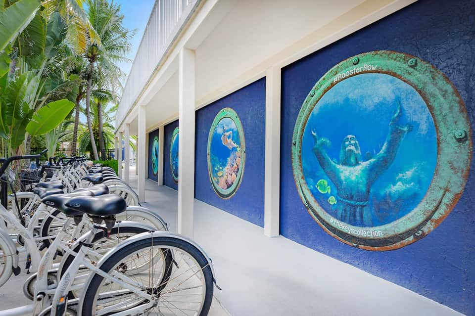 Bike rental station with white bicycles displayed against blue mural with underwater artwork