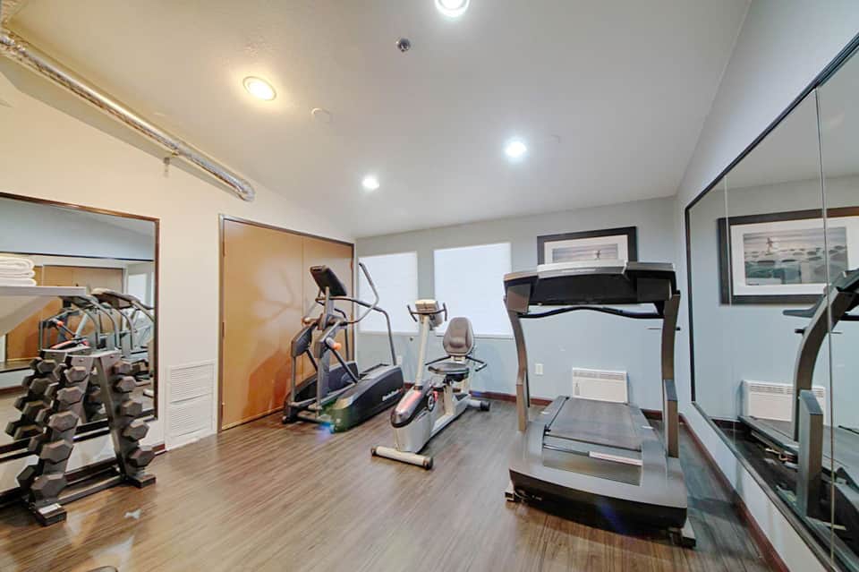 Modern fitness center with treadmills, exercise bike, dumbbells, and mirrors