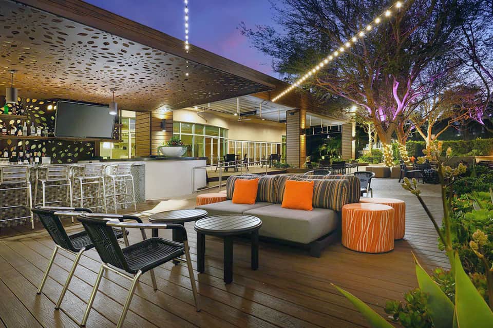 Modern outdoor patio with lounge seating, bar area, and ambient lighting at dusk