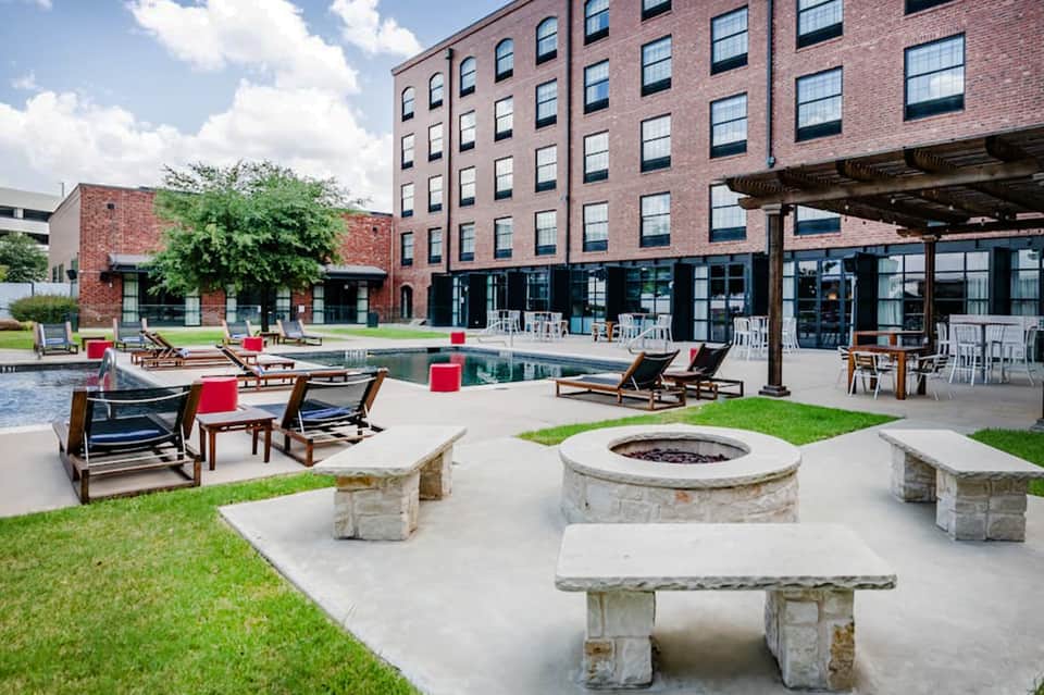 Resort courtyard with fire pits, lounge chairs, and brick building with modern architecture