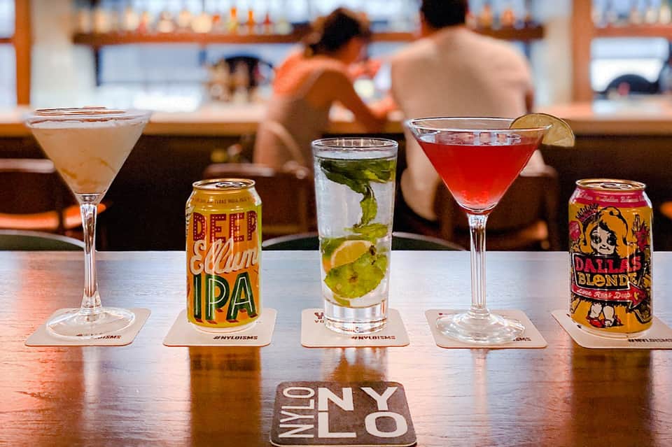 Bar counter displaying craft beers and cocktails with ocean view in background