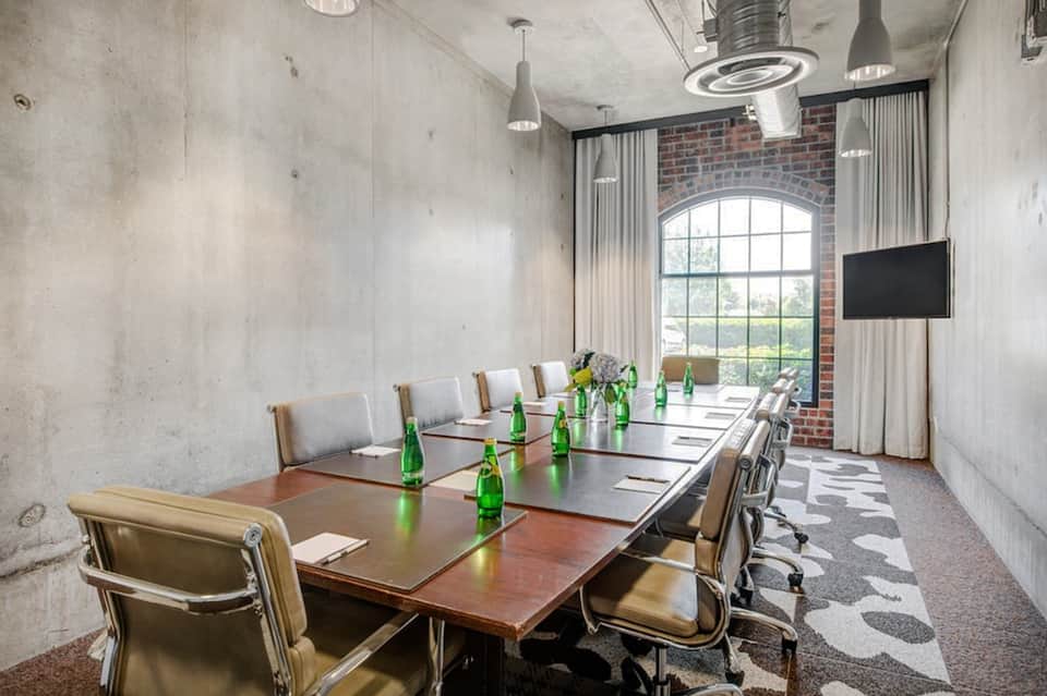 Modern conference room with long table, brick accent wall, and TV