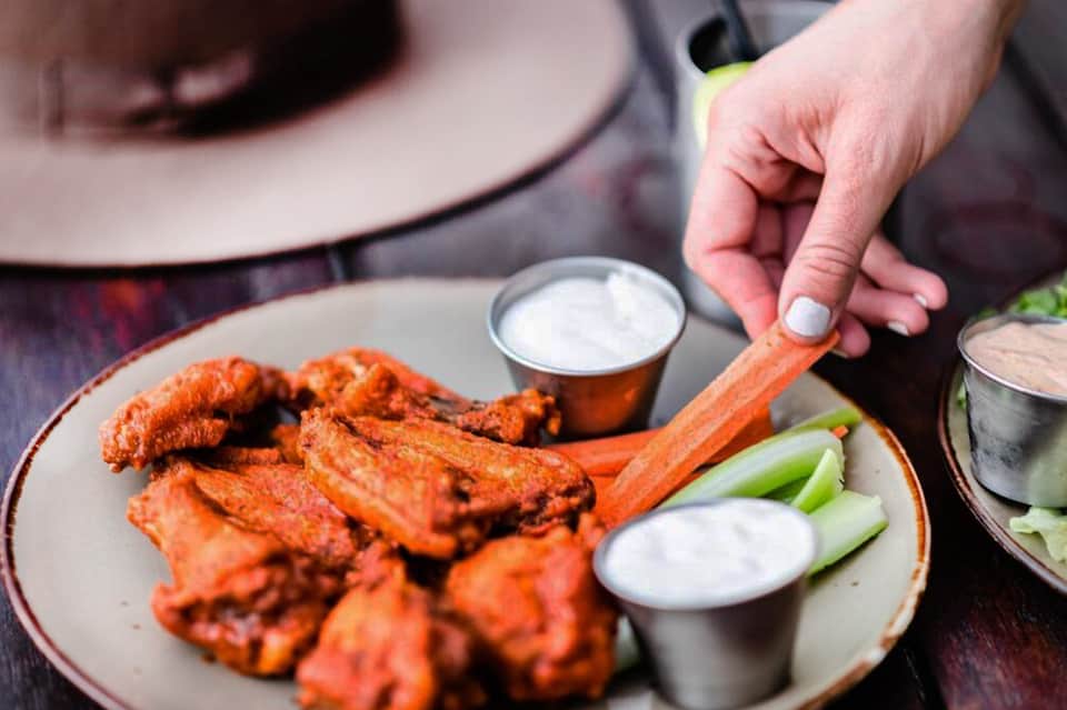 Buffalo wings with celery and dipping sauce on white plate