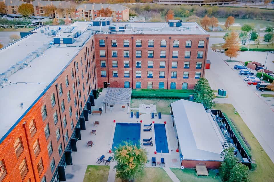 Aerial view of resort courtyard pool surrounded by red brick buildings and landscaping
