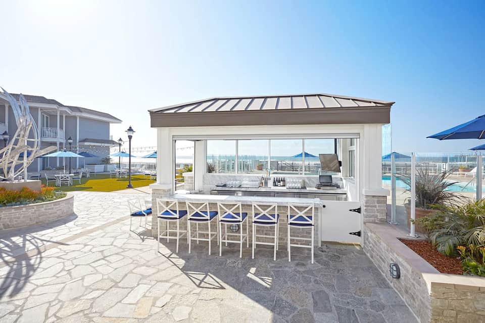 Outdoor bar with white seating overlooking expansive cityscape and mountains