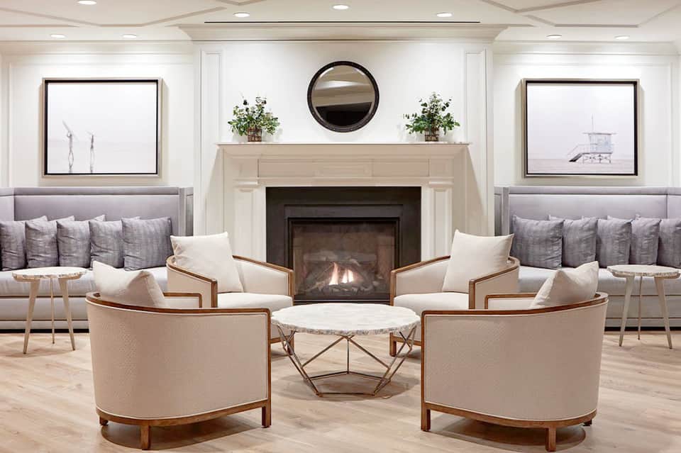 Elegant hotel lobby with fireplace, symmetrical seating areas, neutral furnishings, and modern décor