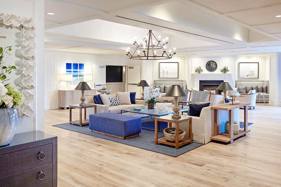 Spacious contemporary hotel lobby with fireplace, blue accents, wooden furniture, and elegant lighting