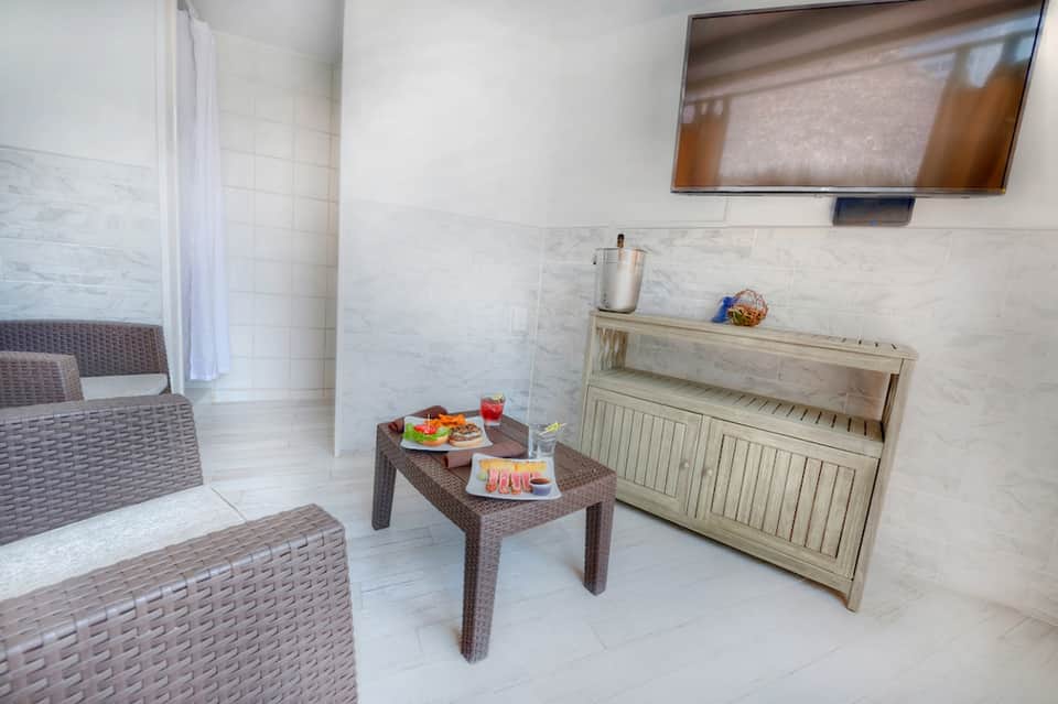 Modern spa relaxation room with wicker seating, small table with snacks and drinks, and TV