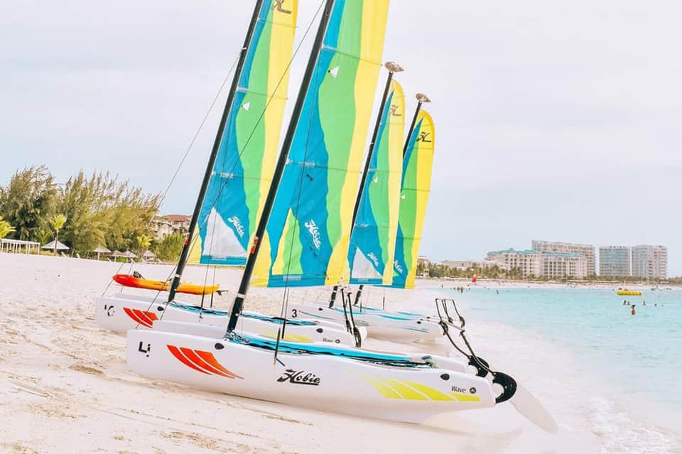 Colorful sailboats with blue, yellow and green sails lined up on sandy beach