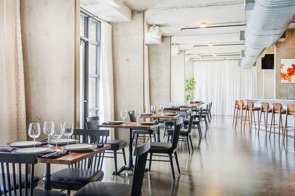 Modern minimalist dining room with wooden tables, black chairs, and polished concrete floors