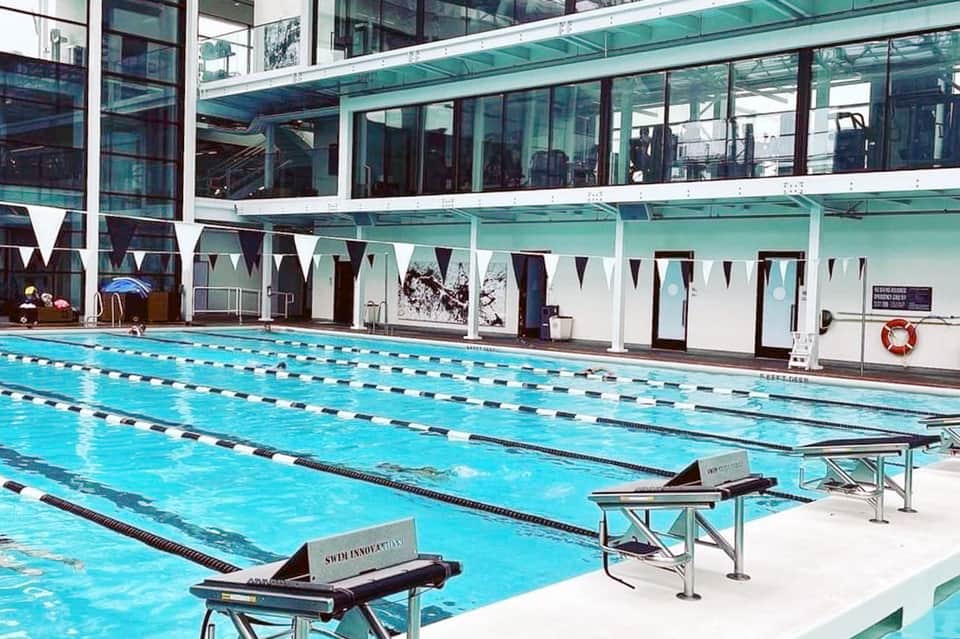 Indoor lap pool with lane dividers, glass ceiling, modern architecture, and competition-style setup