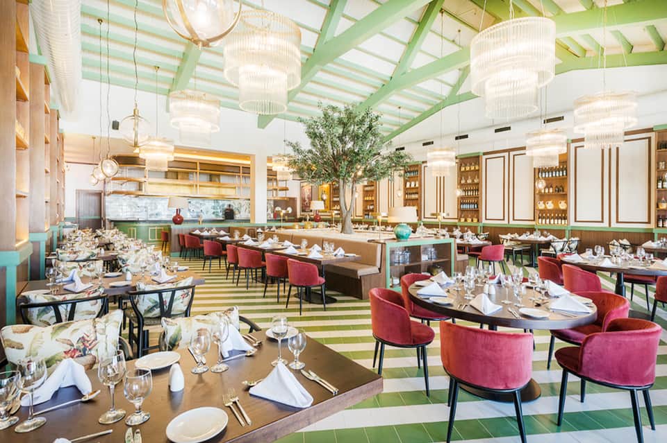 Fine dining restaurant with green striped ceiling, chandeliers, and burgundy chairs