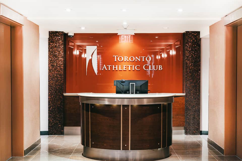 Toronto Athletic Club reception desk with orange accent wall and brick columns