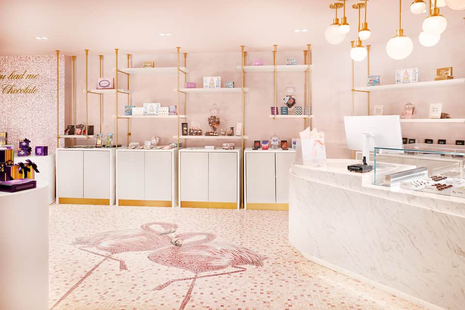 Luxury pink retail boutique interior with gold shelving, marble counter, and decorative display items