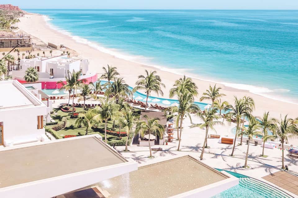 Beachfront resort pools and gardens with white buildings overlooking turquoise ocean
