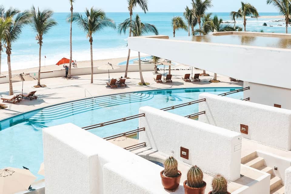 Beachfront pool and spa area with white architecture, palms, and ocean views