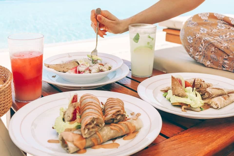 Beachside lunch spread with grilled wraps, fresh salad, and tropical beverages poolside