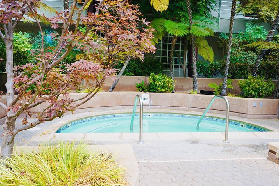Resort pool with metal railings surrounded by lush green landscaping and tropical plants