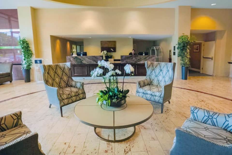 Elegant hotel lobby with round table, patterned chairs, flower arrangement, and dual reception desks