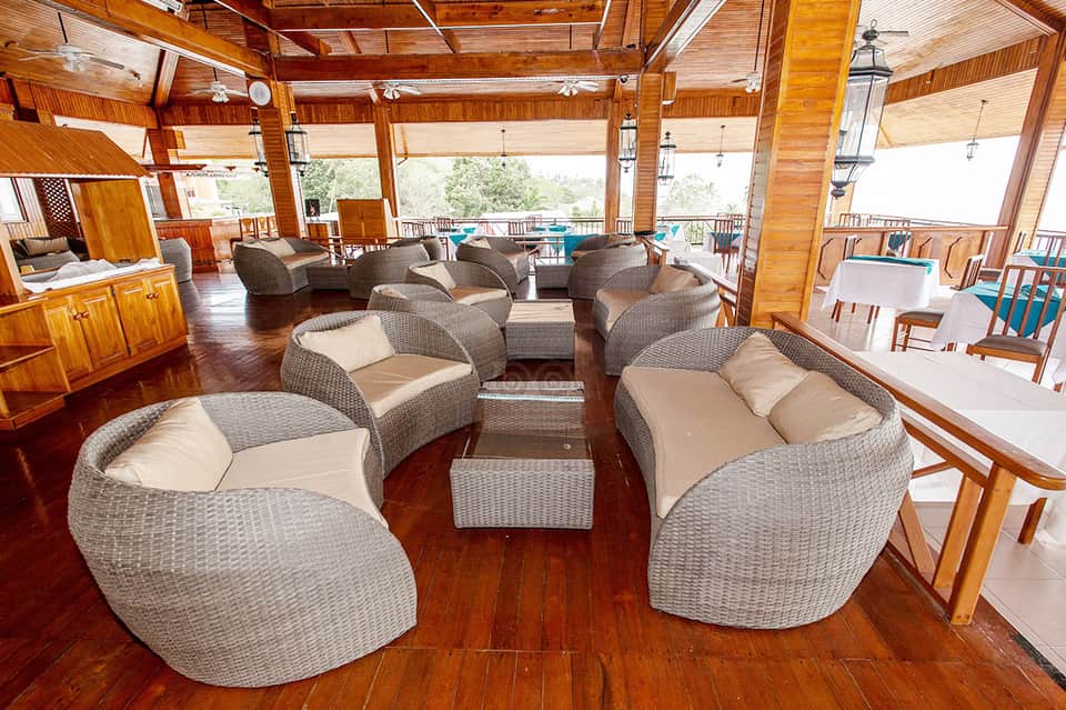 Spacious wooden lounge with woven gray chairs and ocean views from windows