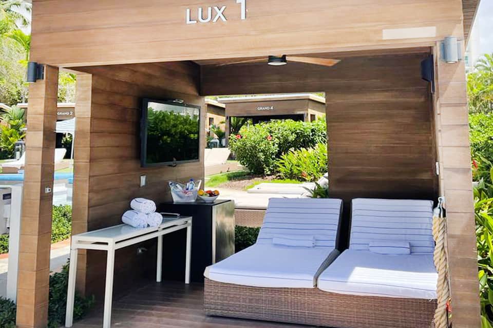 Wooden luxury cabana labeled LUX 1 with cushioned lounge beds and towels inside