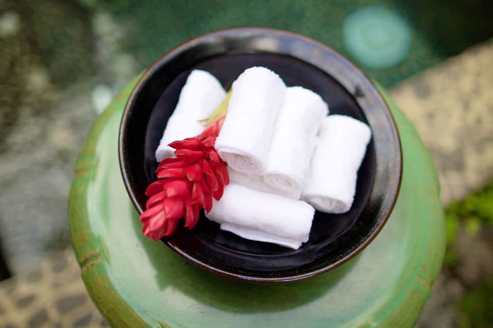 Coconut shell bowl with white towels and red flower spa amenity